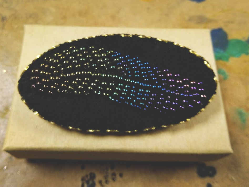 Marie Gonon bijoux création commande sur mesure - broche noire en feutrine avec feuille en broderie de perles aux couleurs dégradées et irisées